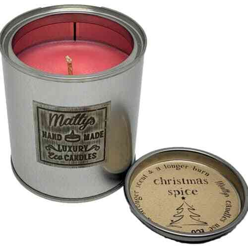 A silver tin labeled "Matty's Handmade Luxury Eco Candles" reveals a pink Christmas Spice Scented Candle, ideal for Christmas. The lid, featuring a small Christmas tree illustration, reads "Christmas Spice.