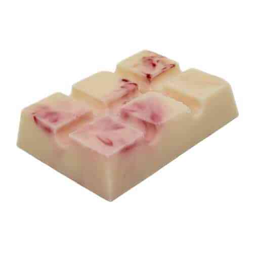 A close-up image of the Dreamy Peach Snap Bar, showcasing its white chocolate blended with pink fruit pieces. The bar is sectioned into small squares, each featuring a hint of pink fruit swirl on top. It is set against a plain white background.