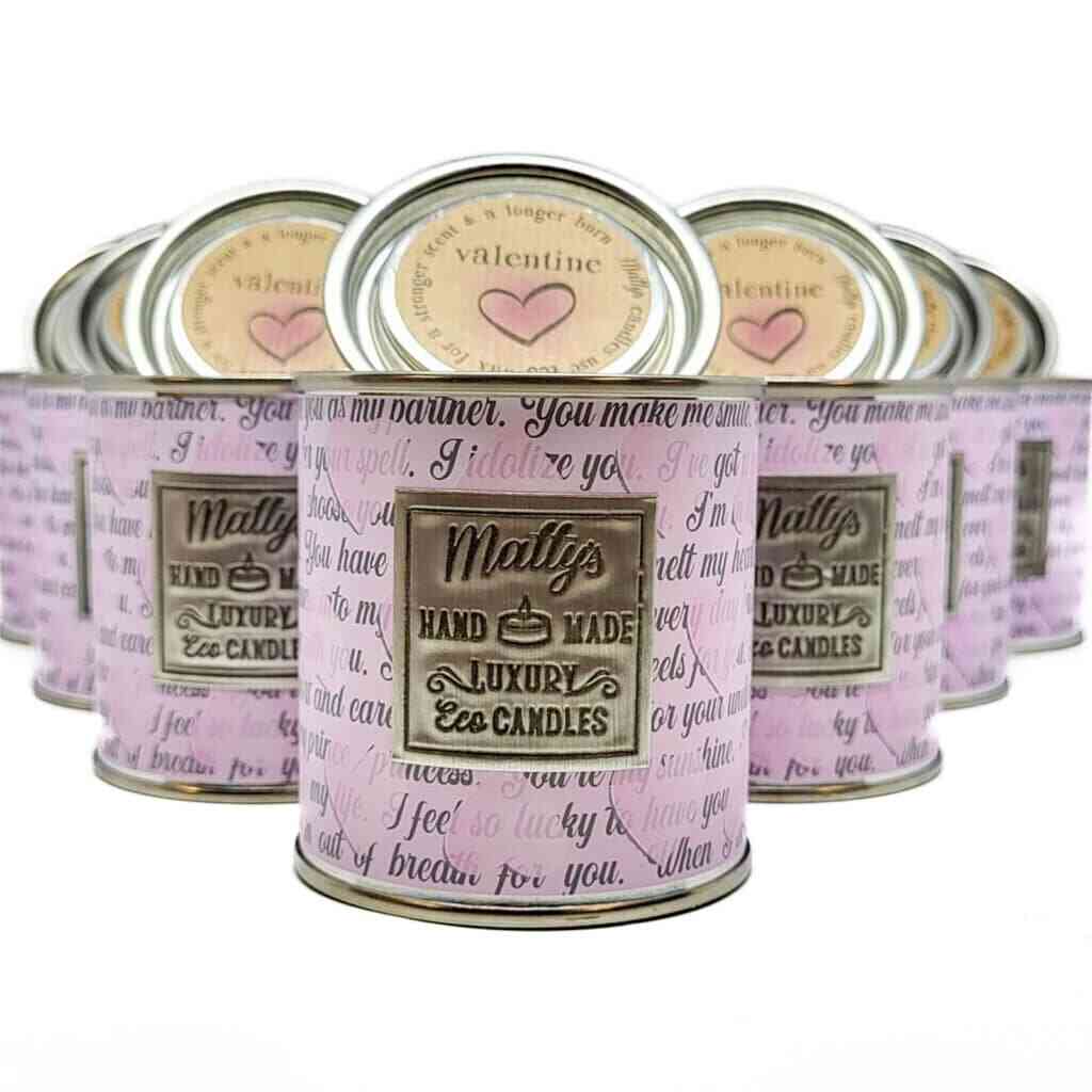 A group of luxury eco scented nottingham candles in cylindrical metal containers with pastel pink labels. The labels feature various messages about love and appreciation. The brand name "Molly's Hand Made Luxury Eco Candles" is prominently displayed on each can.