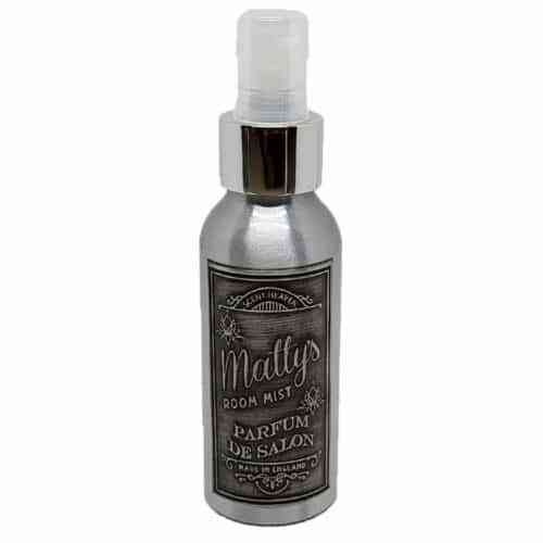 A silver spray bottle with a clear cap labeled "Matty's Room Mist" and "Parfum de Salon," made in England. The label features decorative elements and text in a vintage style.